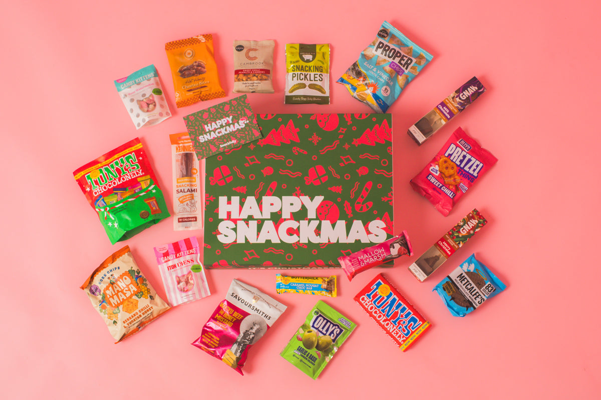 Snackfully Happy Snackmas Christmas gift box and message card surrounded by snacks